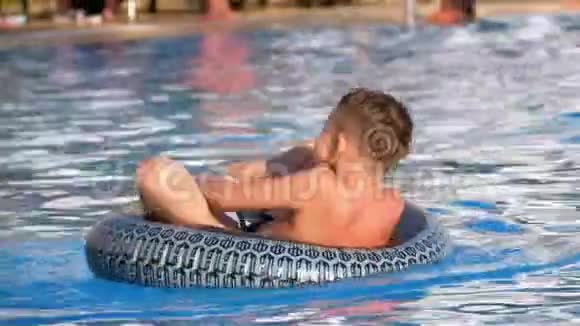 儿童沐浴在一个充气圈在游泳池与蓝色水慢动作视频的预览图