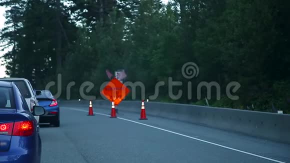 准备停车的明亮橙色标志警告前方道路施工的一队驾车者高清视频的预览图