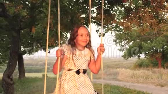 快乐的童年概念孩子们骑着绳子在森林里的橡树树枝上摇摆女孩笑高兴年轻女孩视频的预览图