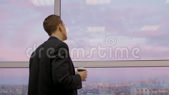 体贴的人带着咖啡透过窗户看美丽的夜空和城市视频的预览图