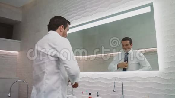 在豪华浴室里系领带的商人快乐的男人打扮自己视频的预览图