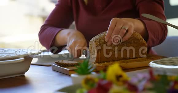 妇女在餐桌上切面包的中间部分视频的预览图