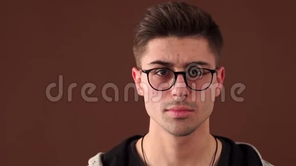 一个带眼镜的情绪激动的年轻人的特写脸他动了动眉毛视频的预览图