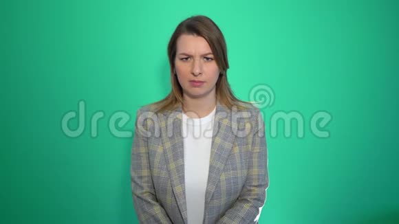 愤怒的金发女孩站在绿色的背景上双臂交叉视频的预览图