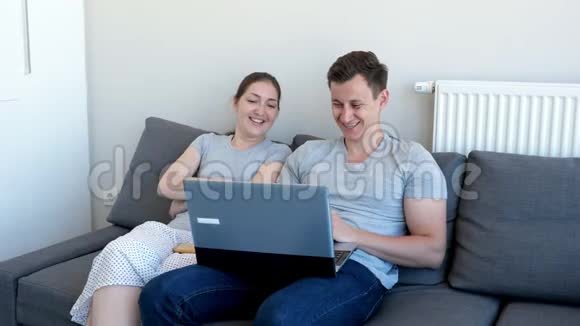 男人和女人坐在沙发上一边看喜剧电影一边笑视频的预览图