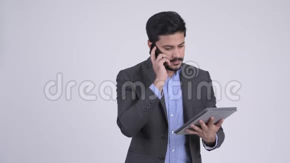 年轻忙碌的印度商人用电话和数码平板电脑聊天视频的预览图