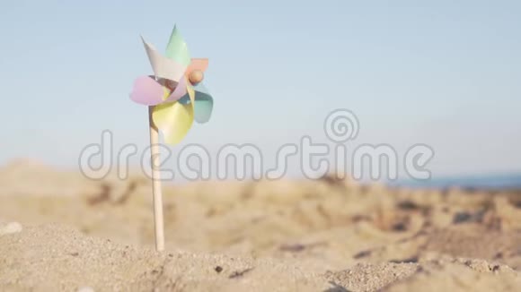 多种颜色的玩具风车粘在沙滩上视频的预览图