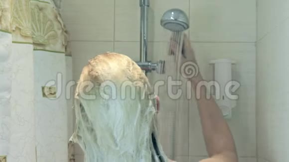 金发女人从头发上洗掉洗发水泡沫洗头和身体护理视频的预览图
