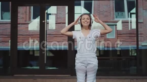 戴着耳机在户外疯狂跳舞的快乐女孩视频的预览图