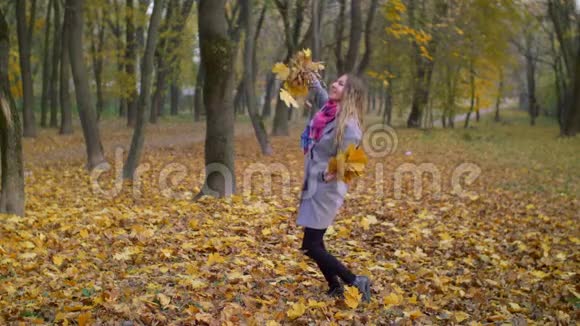 欢乐的微笑的女人在秋天扔树叶视频的预览图
