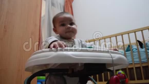 低角度射击可爱的六个月大的男婴在步行者早期发育学习如何走路视频的预览图