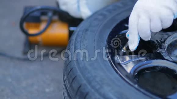 女性戴手套的手插入压缩机线用于泵入盘上的汽车轮胎视频的预览图