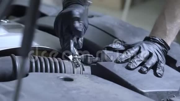 汽车维修工人拧开汽车引擎盖下的螺栓它修理汽车检查性能视频的预览图