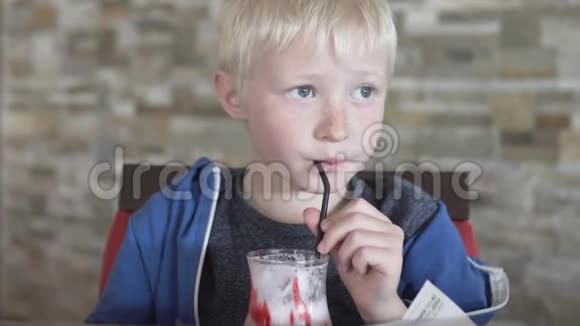 可爱的金发男孩喝草莓奶昔视频的预览图