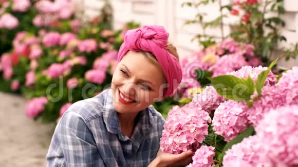 女人在乡下房子里关心粉红色的花爱护花朵的观念令人难以置信的美丽的粉红色花蕾视频的预览图