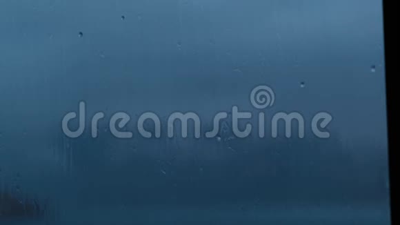 强烈的雨水冲在深蓝色的窗户玻璃上在流下来关闭视频的预览图