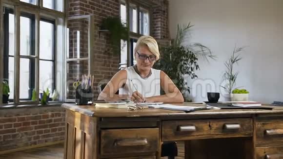 忙碌的成年妇女带着文件和账单在家里办公室用计算器做报告商业会计和人事视频的预览图
