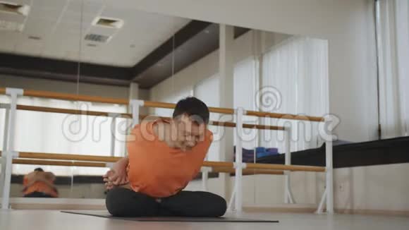 年轻的运动男子在工作室做阿什唐瑜伽一个男人在镜子附近的黑色垫子上做一个体式动作生活方式健康视频的预览图