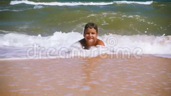 微笑的男孩躺在沙滩上冲浪视频的预览图