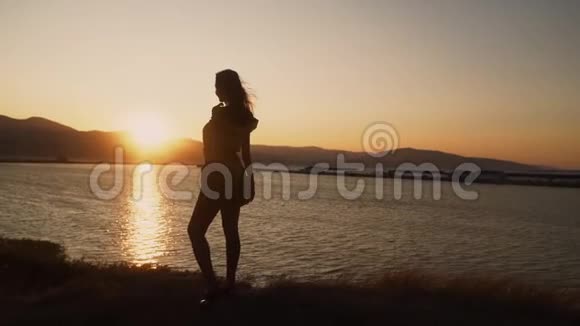 年轻女子看着海滩上美丽的日落慢动作视频的预览图