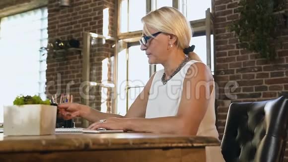 美丽的白种人成年女性在工作场所拿着一杯热咖啡商务女性坐着视频的预览图