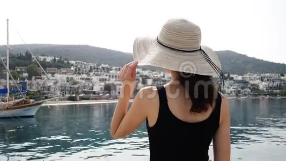 戴圆帽的女孩欣赏港口景观的美博德鲁姆度假小镇上有白色的房子视频的预览图