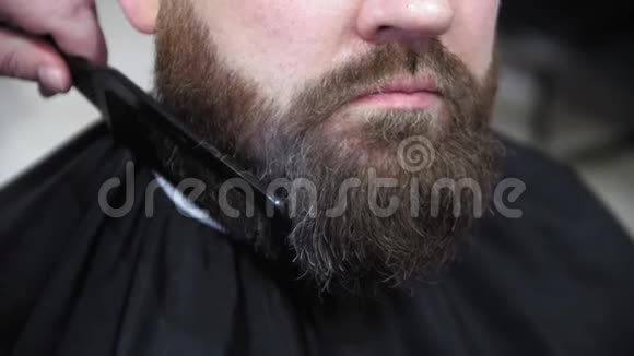去梳胡子理发师在浅色背景的理发店里用专业的胡须修剪器剪下客户的胡须靠近视频的预览图