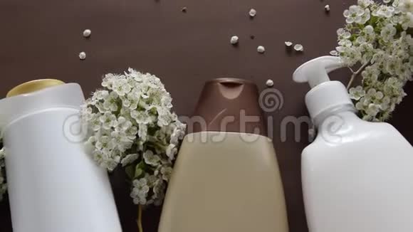 棕色背景下的卫生化妆品和花卉的顶部视图健康美容治疗视频的预览图