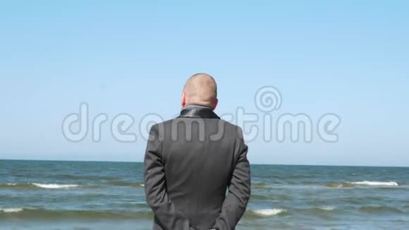 时髦的男人表现得像手势微笑和眨眼优雅自信的年轻商人在海滩上商务视频的预览图