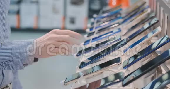 一位男士的特写镜头他的手正在一家电子商店的店面附近买一部新的智能手机视频的预览图