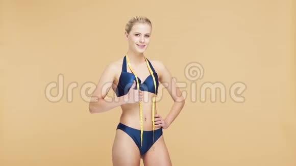 年轻美丽健康自然的金发碧眼的女人穿着蓝色泳衣测量着她完美的身材运动健身护肤视频的预览图