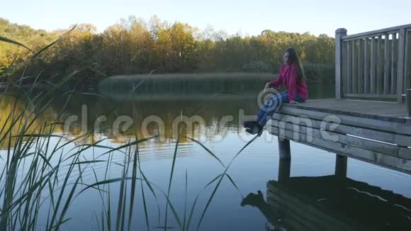 年轻女子在湖边码头放松视频的预览图