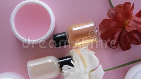 在新鲜的粉红色背景下可以看到不同的卫生化妆品产品和鲜花健康美容治疗视频的预览图