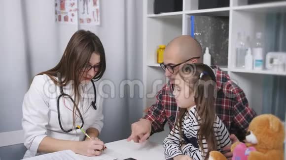 医生命令医学诊所的女医生为孩子写了一份作业父亲视频的预览图