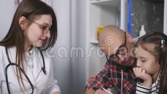 医生命令医学诊所的女医生为孩子写了一份作业父亲视频的预览图
