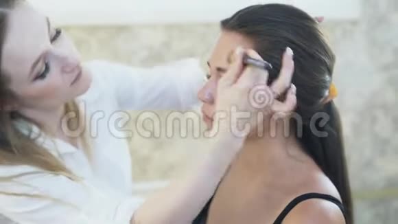 工作中的化妆专家化妆师把色调运用到客户脸上混合了视频的预览图
