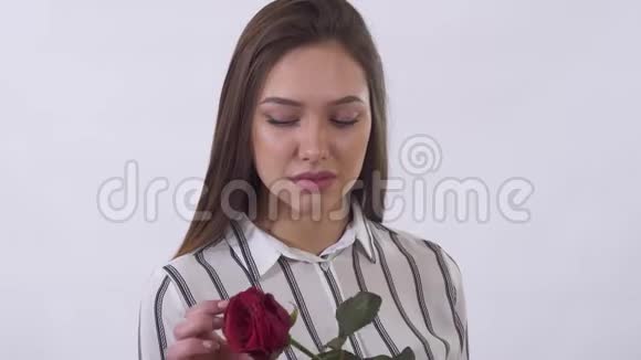 特写肖像悲伤的年轻美女从红玫瑰中拉起花瓣在画室里用白色拍摄视频的预览图