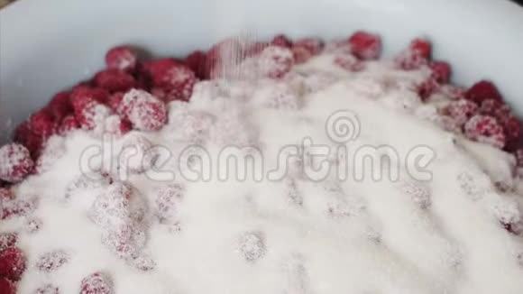 烹饪覆盆子的过程家庭主妇把糖倒入一碗覆盆子里视频的预览图