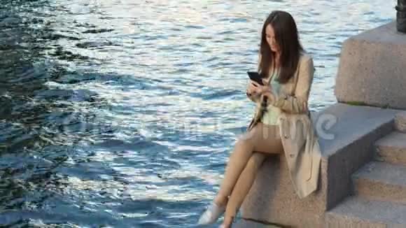 商务女性使用坐在码头河的智能手机视频的预览图