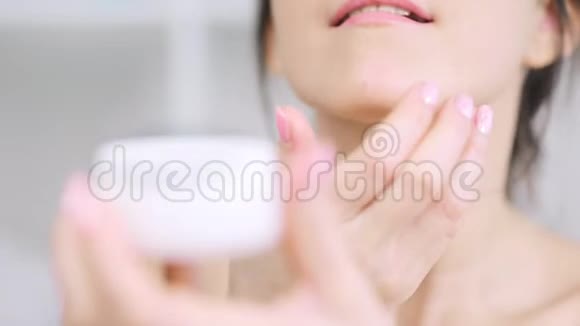 极致特写女性手在下巴涂抹白色保湿霜视频的预览图