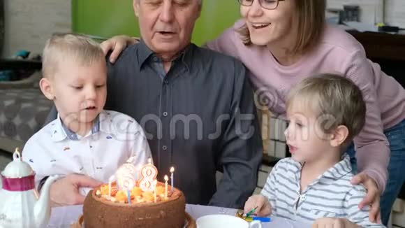 祖父在家庭聚会上吹生日蛋糕蜡烛庆祝生日视频的预览图