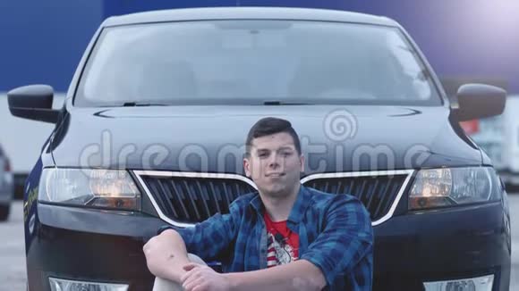 年轻英俊的男子笑得很开心坐在他的新汽车前视频的预览图