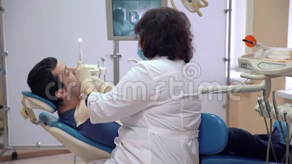 牙科医生给病人治牙一个男人躺在牙科诊所的椅子上视频的预览图