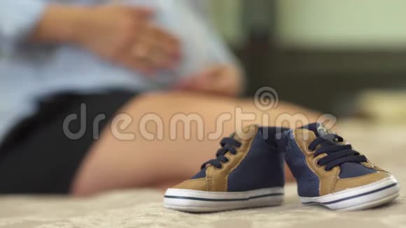 孩子们运动鞋躺在一个怀孕女孩旁边的床上视频的预览图
