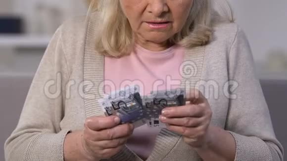 不高兴的老妇人数着欧元钞票养老金少缺钱贫穷视频的预览图