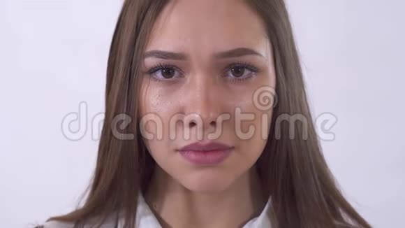 悲伤的年轻女子在演播室的白色背景下哭泣的肖像耳朵沿着脸颊往下跑视频的预览图