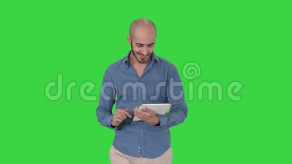 阿拉伯男人在绿色屏幕上行走和使用平板电脑上网Chroma键视频的预览图