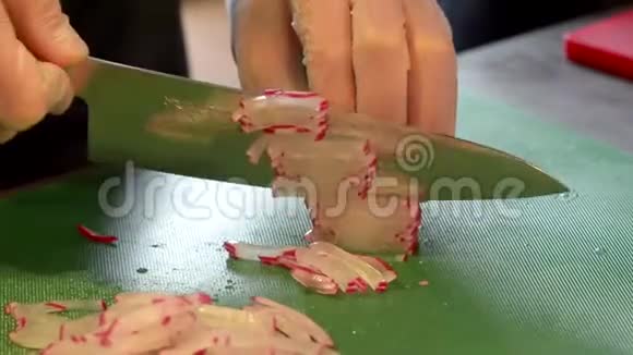 一个戴着刀切萝卜的手套的人在一个切割板上视频的预览图