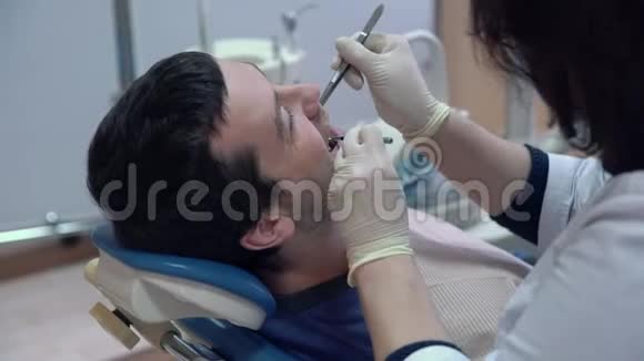 一位戴着无菌口罩和衣服的牙医用医疗器械在病人口做手术视频的预览图