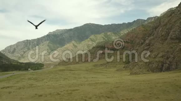 在夏日的背景下在带有山脉的乡村道路上鸟瞰风景大道飞鹰飞过视频的预览图
